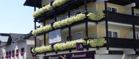 A multi-story building with balconies adorned with white flowers.