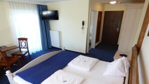 A hotel room with a bed, a desk, a chair, a television, and a telephone. - Panoramahotel (Sankt Johann in Tirol)