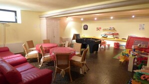 A room with a pool table, red lounge chairs, wicker chairs around a small table, and a foosball table. - Panoramahotel (Sankt Johann in Tirol)