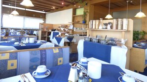 A restaurant with multiple tables set for dining, featuring blue tablecloths and white plates. - Panoramahotel (Sankt Johann in Tirol)