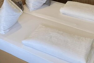 En pænt redt seng med hvide sengetøj og puder.