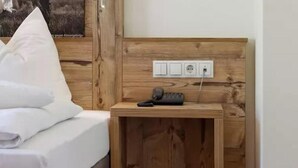 A wooden headboard with a bedside table, a phone, and a power outlet. - Ferienhotel Fuchs (Soell)