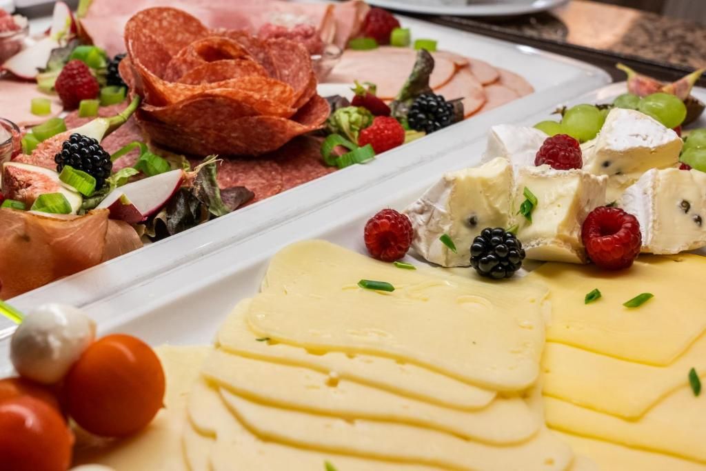 Une planche de charcuterie avec divers fromages, fruits et viandes.