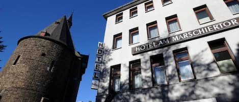 A hotel with a prominent tower and a sign reading "HOTEL AM MARSCHIERTOR".