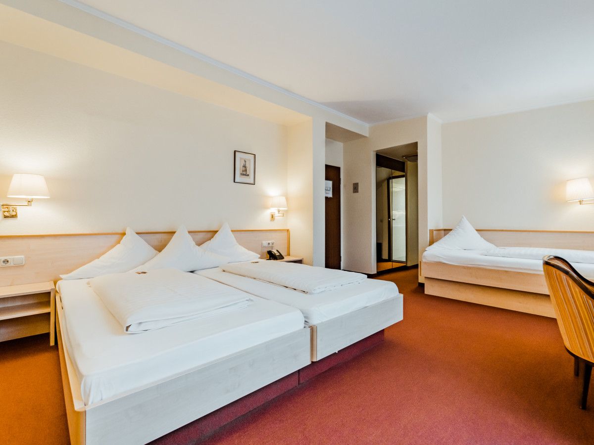 Una habitación de hotel con dos camas, una silla y un escritorio.