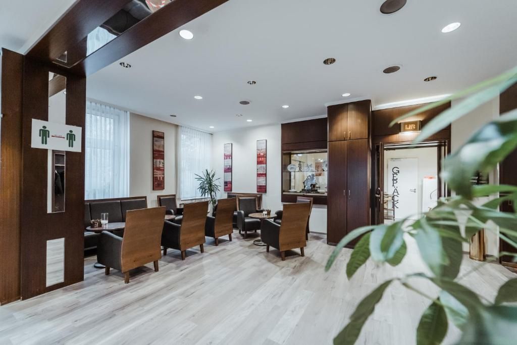 A modern hotel lobby with wooden paneling, a reception desk, and a seating area with chairs and tables.