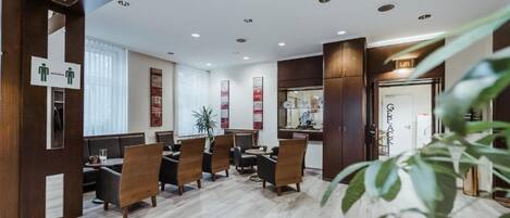 A modern hotel lobby with wooden paneling, a reception desk, and a seating area with chairs and tables.
