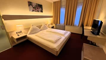 A hotel room with a large bed, bedside tables with lamps, a TV, and a painting on the wall.