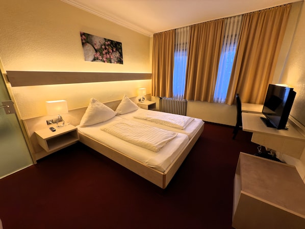 A hotel room with a large bed, bedside tables with lamps, a TV, and a painting on the wall. - Hotel Am Marschiertor (Aachen)