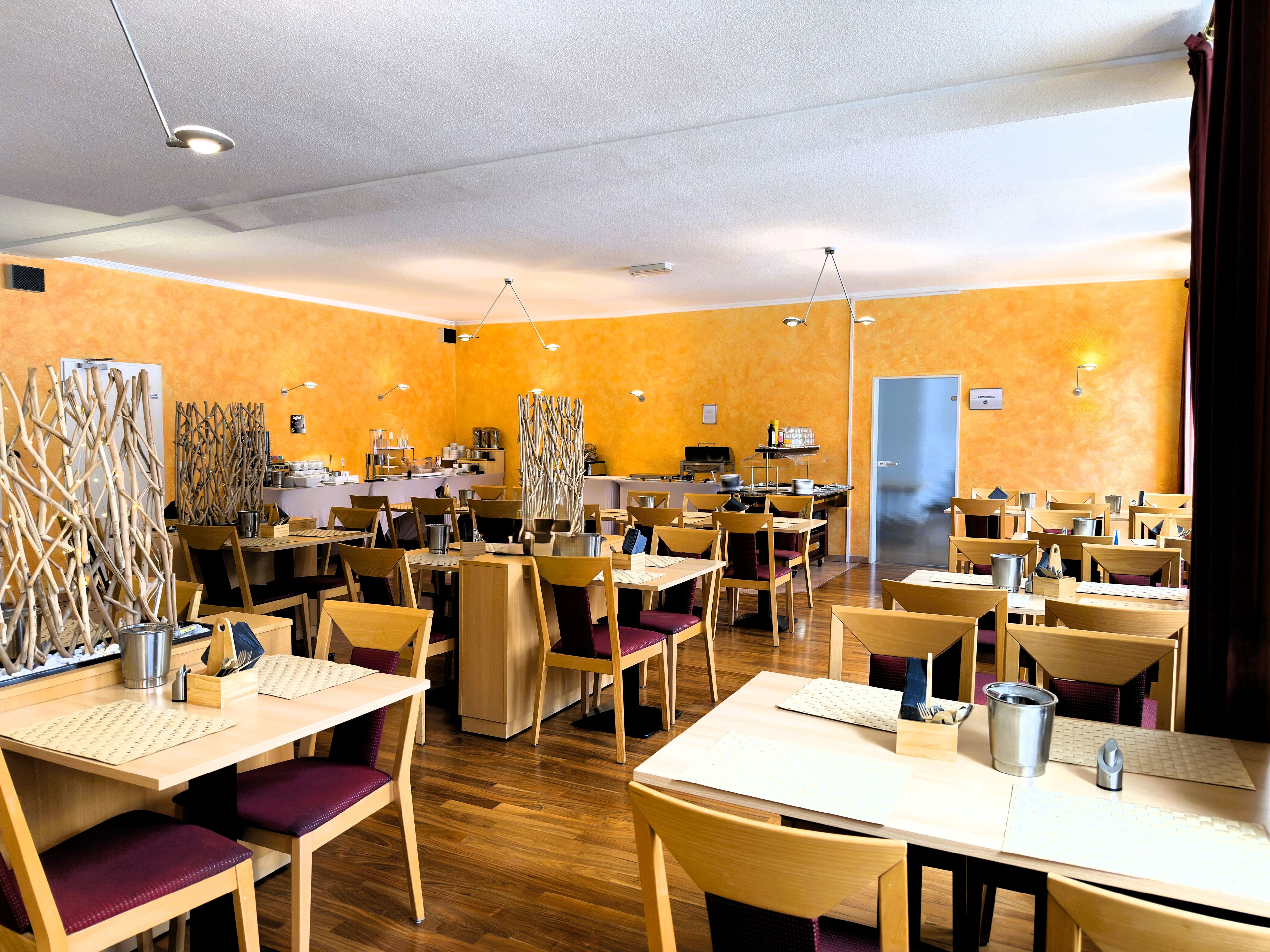 Un restaurante con varias mesas y sillas, una zona de cocina y una puerta.
