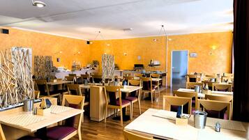 Un restaurante con varias mesas y sillas, una zona de cocina y una puerta.