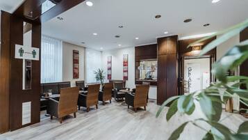 A modern hotel lobby with wooden paneling, a reception desk, and a seating area with chairs and tables.