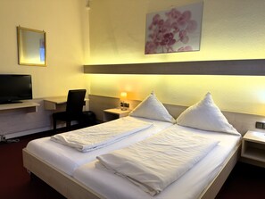 A hotel room with two beds, a TV, a desk, a chair, and a lamp. - Hotel Am Marschiertor (Aachen)