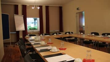 A conference room with a long table, chairs, a whiteboard, and a window with curtains.
