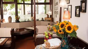 A cozy restaurant interior with a booth seating area, a table with a vase of sunflowers, and a vintage sewing machine.