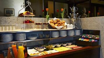 A buffet setup with various food items, including fruits, pastries, and beverages.