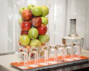 A glass container filled with apples and shot glasses on a tray. - Sternsoller (Ismaning)