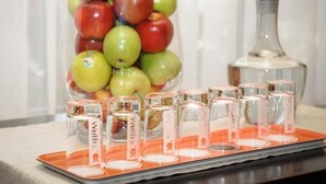 A glass container filled with apples and shot glasses on a tray. - Sternsoller (Ismaning)