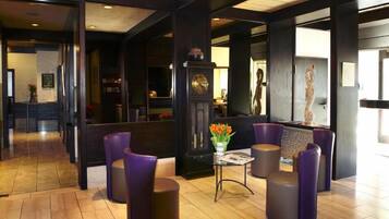 A lobby with a reception desk, purple seating, a clock, and a vase with flowers.