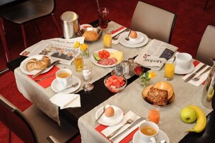 Una mesa de desayuno dispuesta con platos de huevos, tostadas, fruta y bebidas, junto con un periódico.