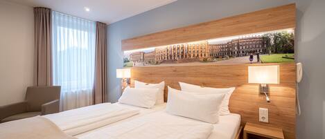 A hotel room with two beds, a wooden headboard, a chair, and a view of a building through a window.