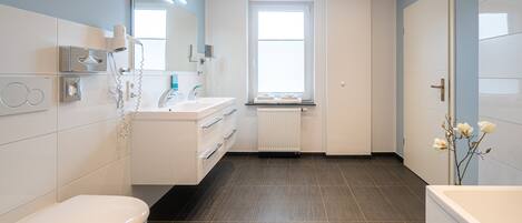 Un baño moderno con inodoro, lavamanos, espejo y ventana.