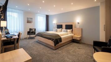 Una habitación de hotel moderna con una cama grande, un escritorio, una silla y un televisor.