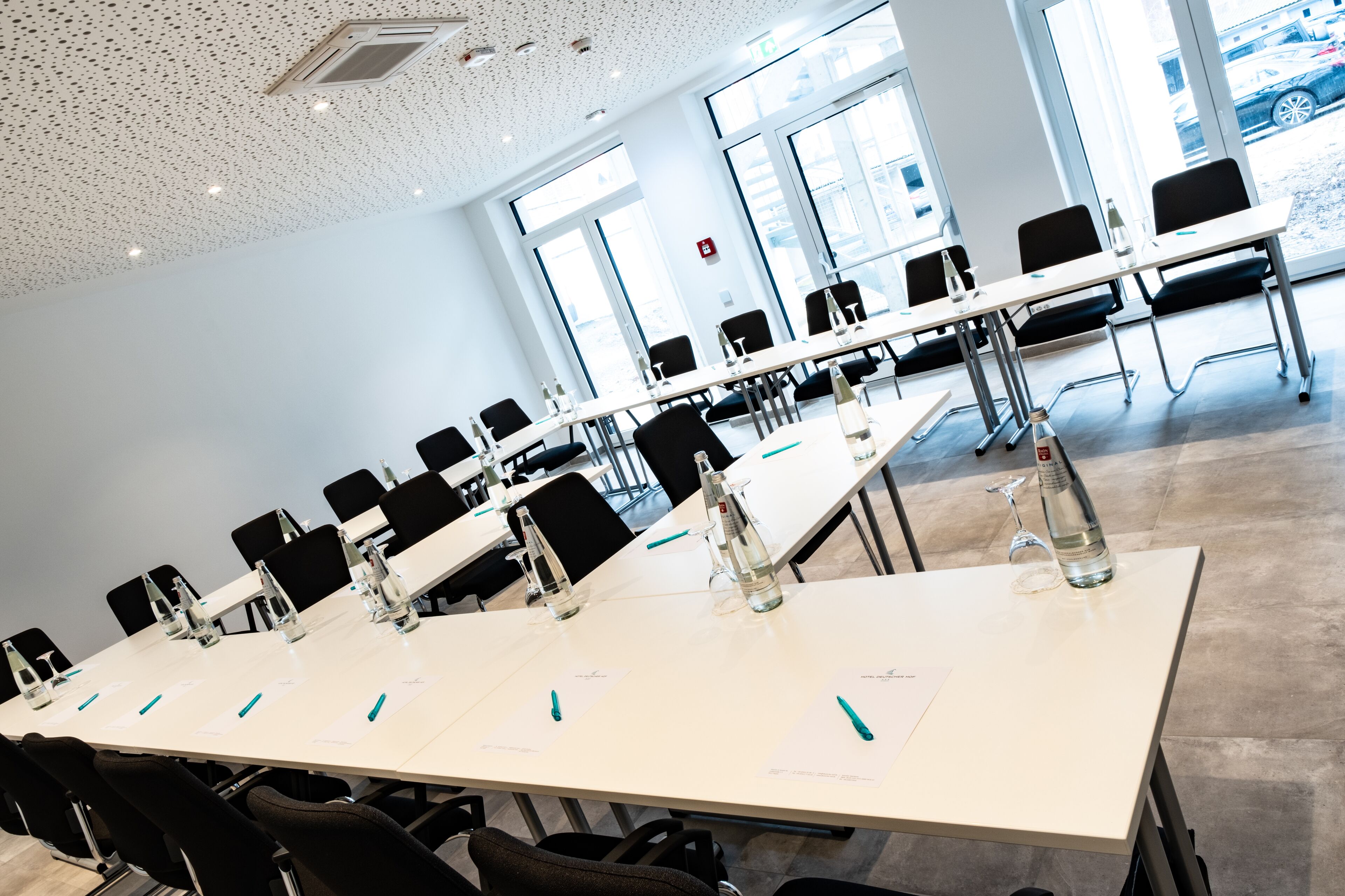 A conference room with long tables, chairs, water bottles, and papers.