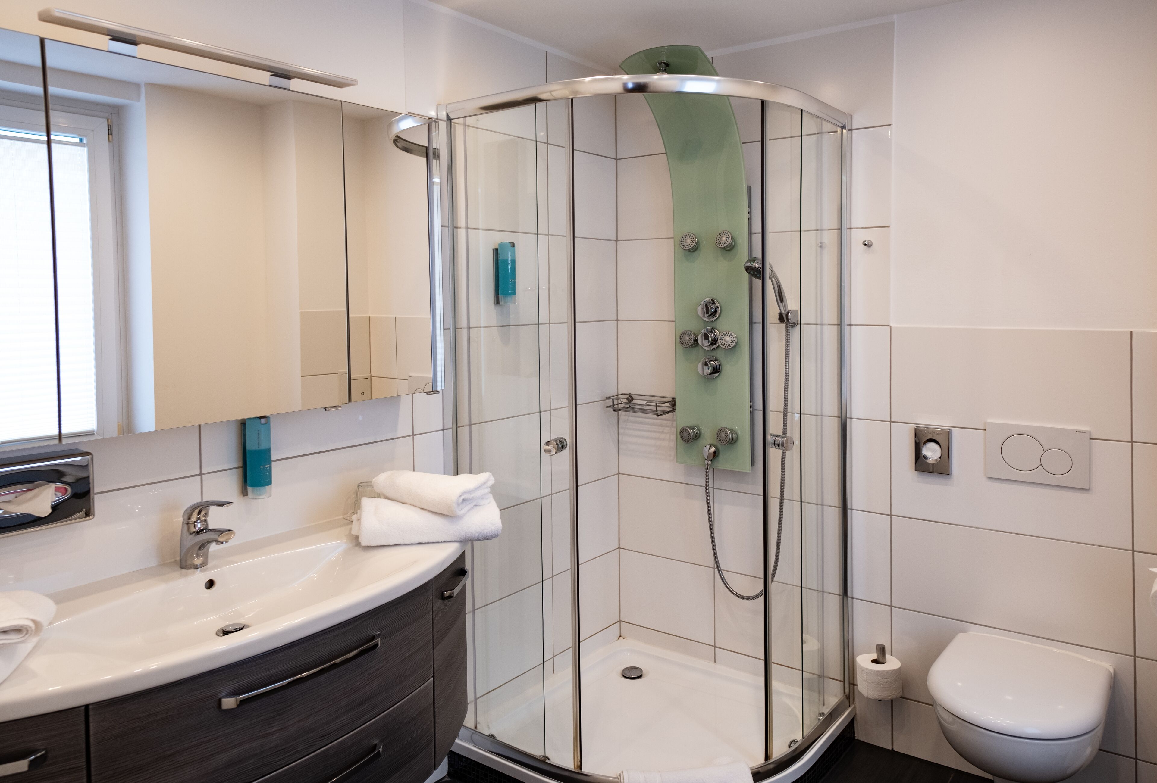 Une salle de bain moderne avec une douche à parois de verre, un lavabo avec un miroir et des toilettes.