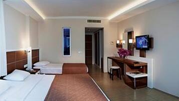 A hotel room with two beds, a desk, a TV, and a bathroom.