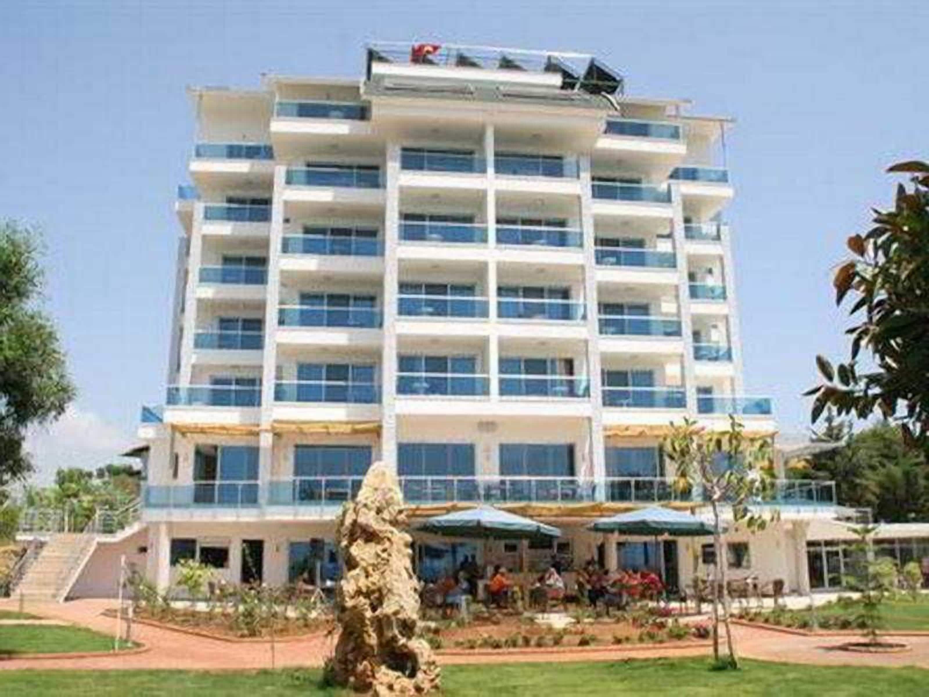 Um hotel com vários andares, um pátio central, área de estar externa e uma escultura de pedra.