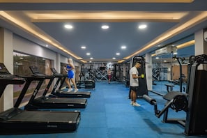 Una palestra con tapis roulant, macchinari per pesi e uno specchio a parete.
