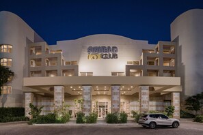 Un hôtel moderne, avec une enseigne bien visible portant l’inscription « SINDBAD CLUB », et une voiture garée devant.