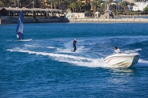 A water body with a boat and a person on a wakeboard. - Sindbad Club (Hurghada)