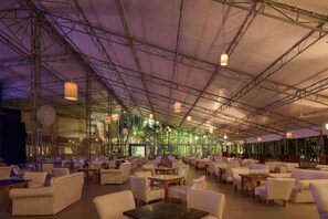 An indoor venue with a high ceiling, numerous tables and chairs, and a central area with a large screen. - Sindbad Club (Hurghada)