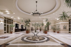 A spacious lobby with a central round table, multiple potted plants, and a chandelier. - Sindbad Club (Hurghada)