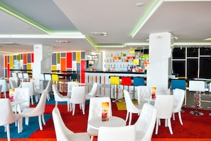 A modern bar area with white bar stools and a variety of colorful bottles on shelves. - Grifid Hotel Encanto Beach (Varna)