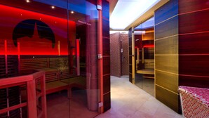 Eine moderne Sauna mit Glaswänden, einer Holzbank und roter Beleuchtung.