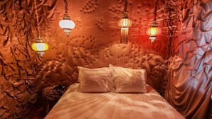 A bedroom with a tufted headboard, a bed with white linens, and hanging lantern-style lights. - Hotel The Exchange (Amsterdam)