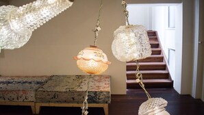 A room with a wooden bench, a staircase, and hanging crystal chandeliers. - Hotel The Exchange (Amsterdam)