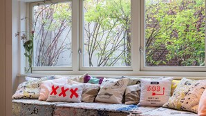 A bed with a patterned bedspread and multiple pillows, including one with a red 'X'. - Hotel The Exchange (Amsterdam)