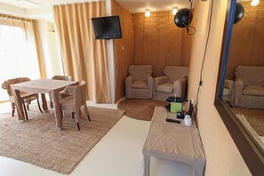 A room with a wooden wall, a television mounted above a seating area, and a table with chairs. - Hotel The Exchange (Amsterdam)