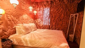 A bedroom with a tufted headboard, a bed with white linens, and a curtain with a crinkled pattern. - Hotel The Exchange (Amsterdam)