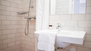 A bathroom with a white sink, a shower, and a mirror. - Hotel The Exchange (Amsterdam)