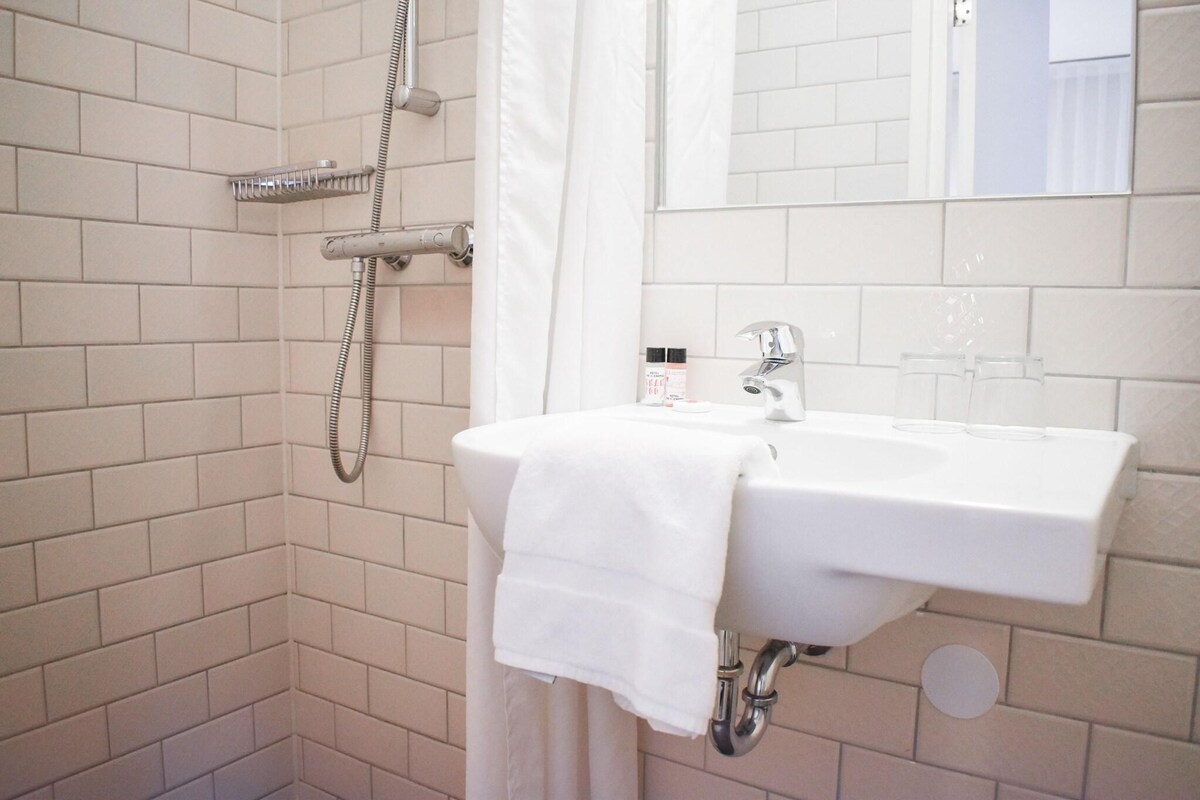 A bathroom with a white sink, a shower, and a mirror.