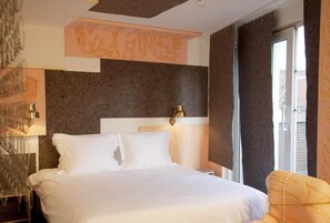 A hotel room with a large bed, two bedside lamps, a headboard, and a window with curtains. - Hotel The Exchange (Amsterdam)