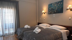 A hotel room with two beds, a painting on the wall, and two wall lamps. - Achillion Hotel (Larissa)