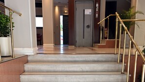 A hotel entrance with marble steps, a doormat with the hotel's name, and a staircase with golden railings. - Achillion Hotel (Larissa)
