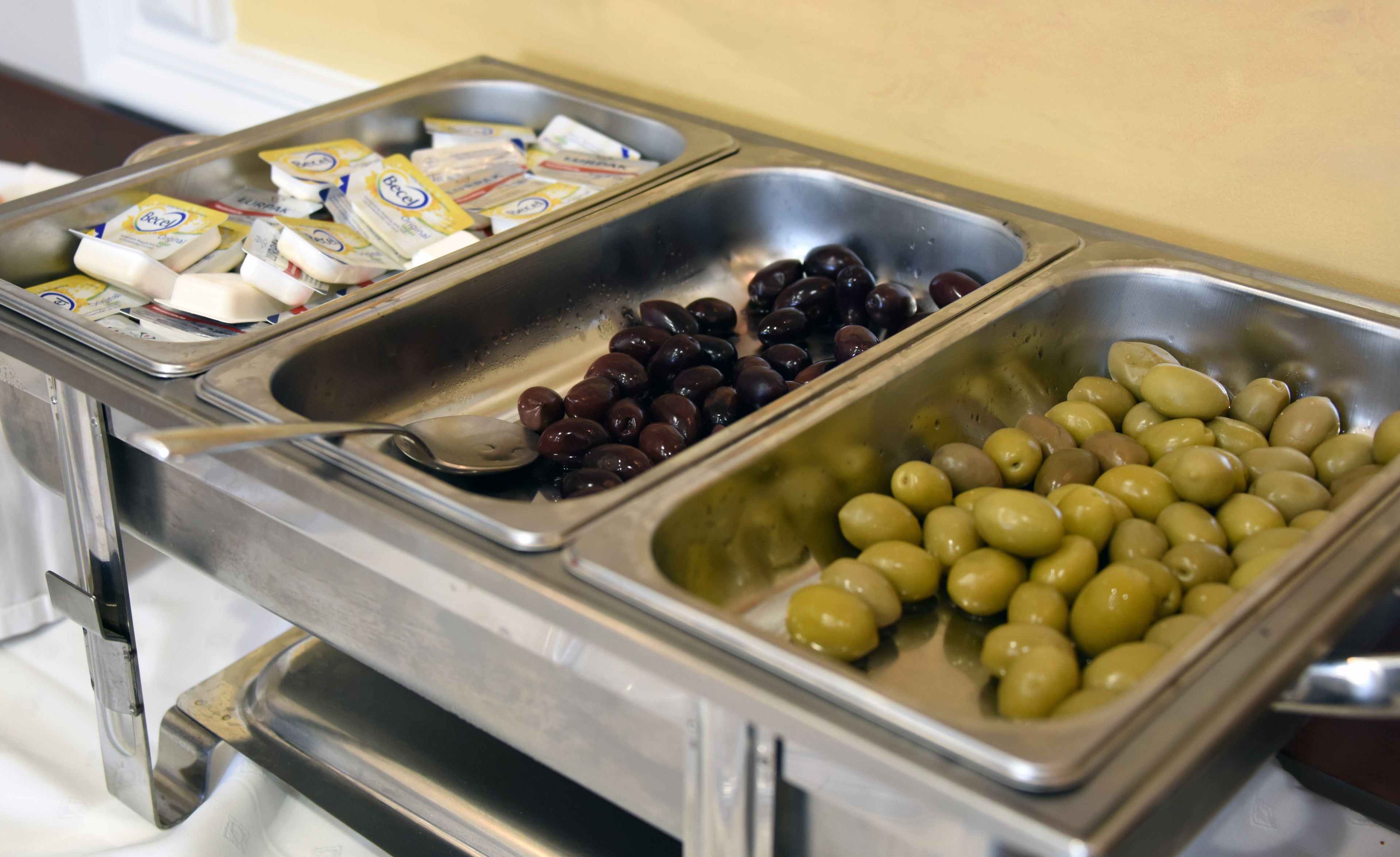 Un bufé con tres bandejas metálicas que contienen distintos alimentos.