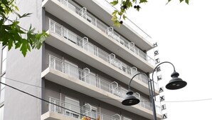 A multi-story hotel with balconies, a street lamp, and a sign indicating the name. - Achillion Hotel (Larissa)